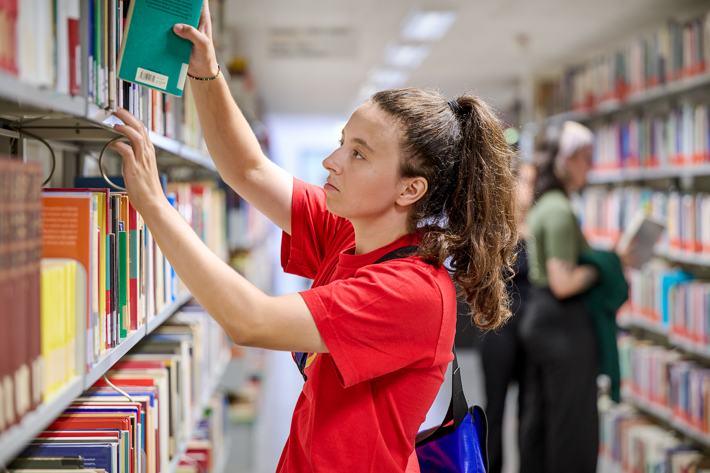 Das Bild zeigt die grosse Glasfront der Bibliothek am Deutschen Seminar. Links und rechts stehen grüne Bäume, davor liegt eine saftige Wiese.